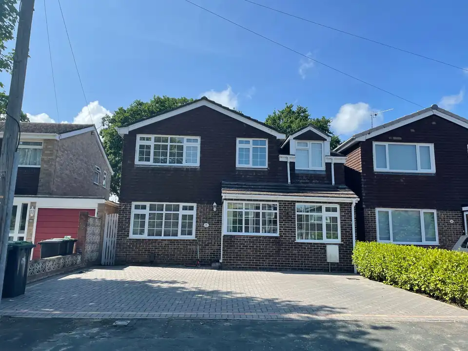 A dark clad house with rows of clean white windows and a block paved drive